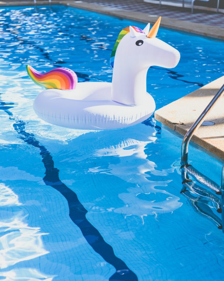Inflatable colorful white unicorn at the swimming pool. Vacation time in the swim pool with toys