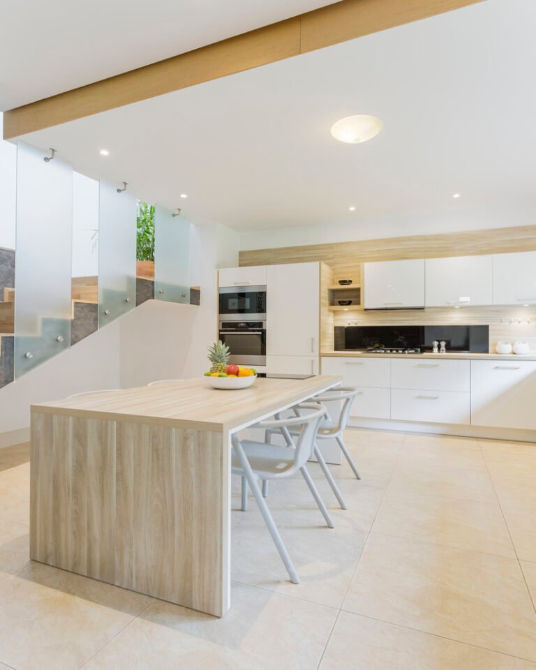 View of open space kitchen with white countertop and bar stools