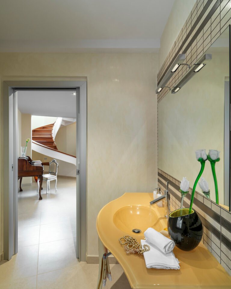 on the right a close-up of a yellow glass wall washbasin in the modern bathroom overlooking the living roomand on the wooden stair