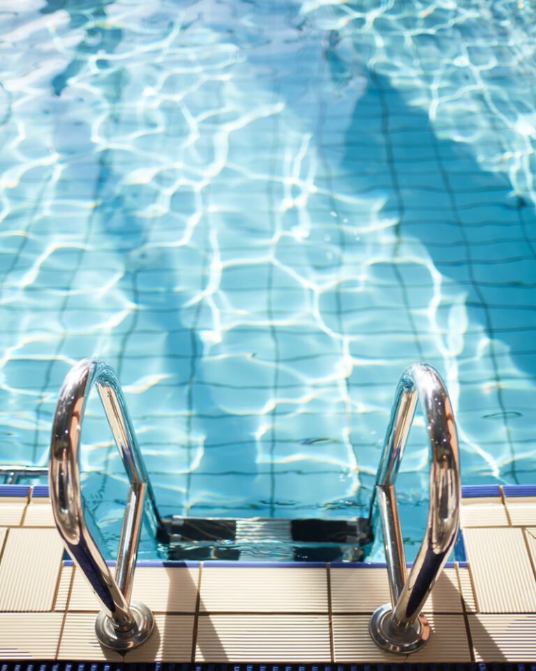 Modern swimming-pool with clean and transparent water and steel railings
